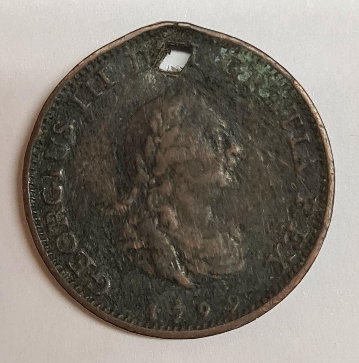 Ett mynt från Storbritanien.
1799
(George III 1760-1801)

Myntet har ett håll i övre kanten.