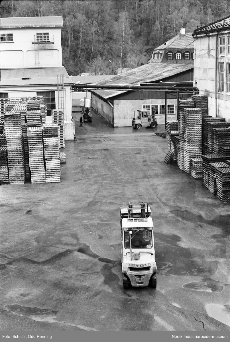 Pallelager og trucker på fabrikkområdet.