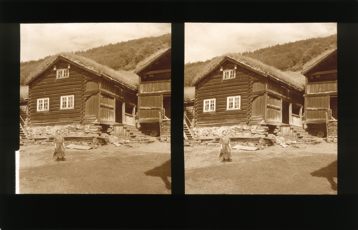 Tunet på Harildstad gård. Det står en kvinne på tunet. Tilhører Arkitekt Hans Grendahls samling av stereobilder.