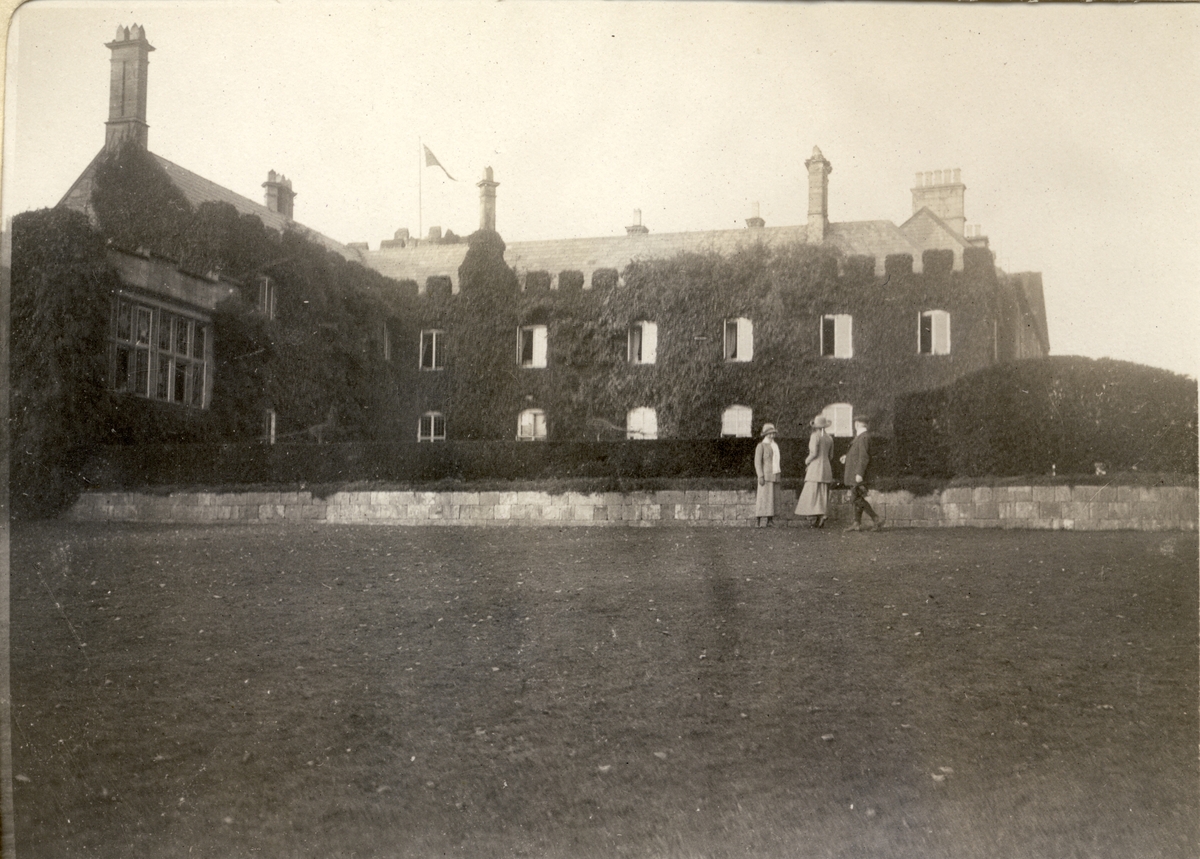 Hovedbygningen på herregården Coldbrook Park i Abergavenny, Wales. To kvinner og en mann spaserer i parken. Fotografert 1913.
