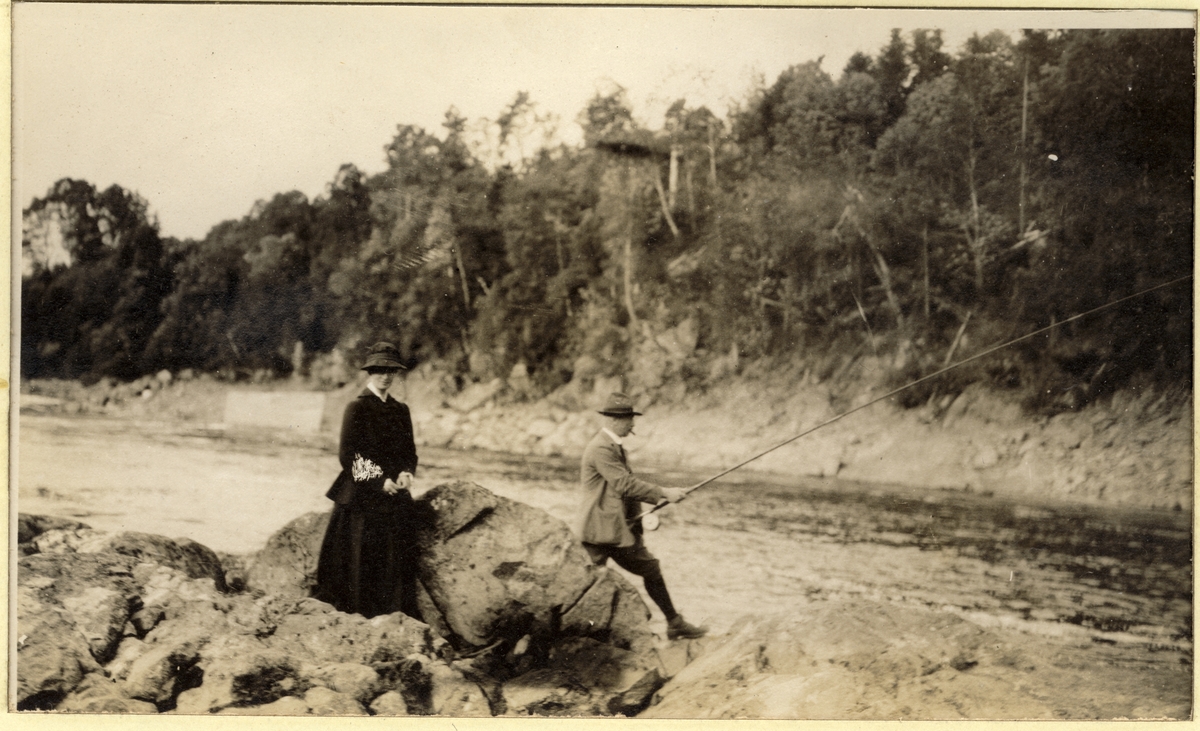 Westye Egeberg fisker i Stubben I Numedalslågen ved Flesberg, med fruen, Nini Egeberg, som tilskuer. Fotografert juli 1916.