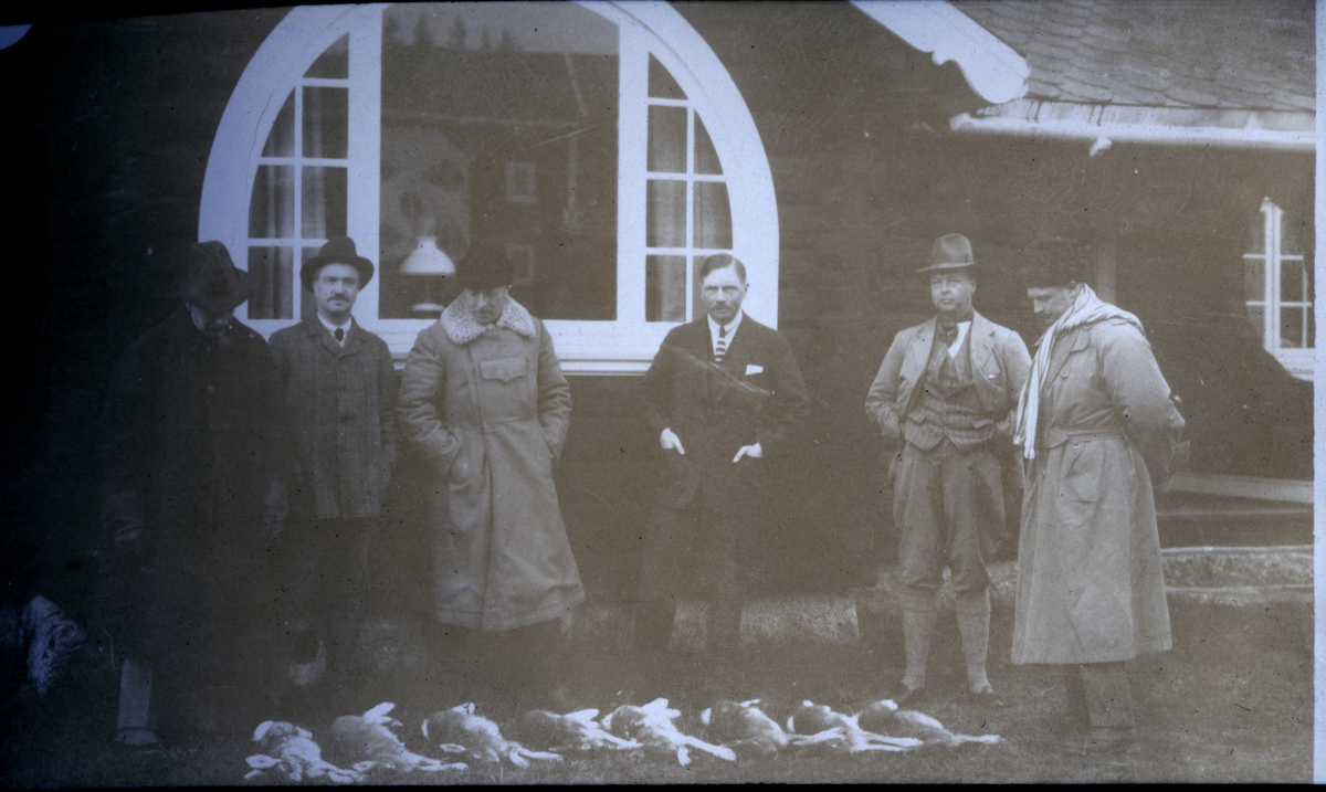 Seks menn samlet etter harejakt foran Egeberg-familiens jaktslott ved Malungen. Foran dem ligger jaktbyttet. Fra venstre antagelig Adolf Eger, oberst Johan M. Nyquist, Søren Sommerfelt, Fritz Treschow, Einar W. Egeberg og Waldemar Kallevig. Fotografert oktober 1922.