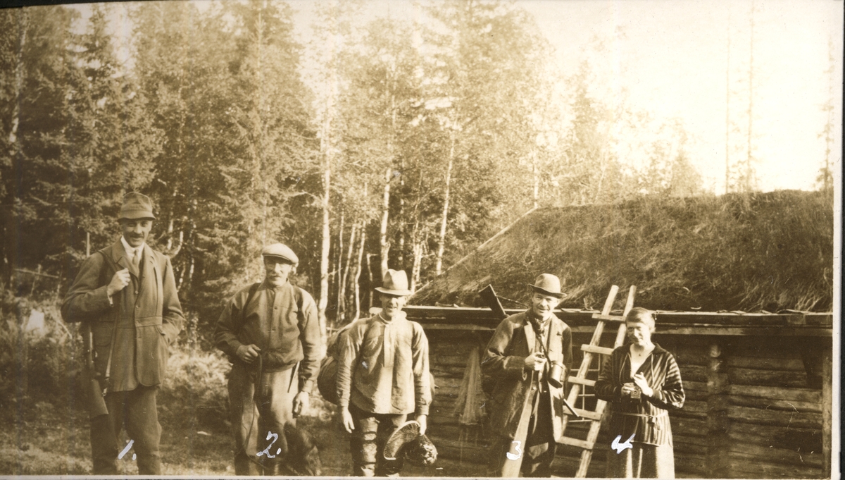Fra elgjakt i Namdalen i september 1923. Fra venstre Oscar Collett, Anton Falmår, ukjent, Harald Platou og fru Mia Collett. I bakgrunnen en laftet jakthytte.