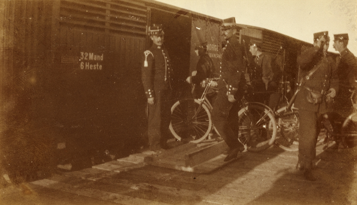 Premierløytnant Hvoslef og kaptein Dietrichson i Søndenfjeldske Hjulrytterkompani sørger for innlasting av sykler i tog på Levanger stasjon. Fotografert 1901.