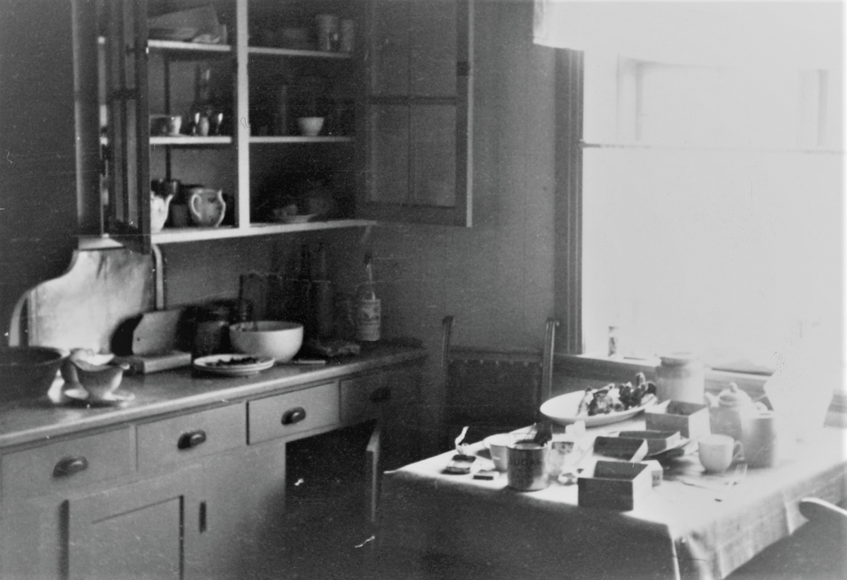 Feiring av freden 1945. Kjøkkenbenk og skap med utstyr. Kjøkkenbord med tomme sigaresker, sukkerbokser osv. Fra et hus i Haugesund som tyske soldater hadde som tilholdssted under okkupasjonen. Forlatt i hast.