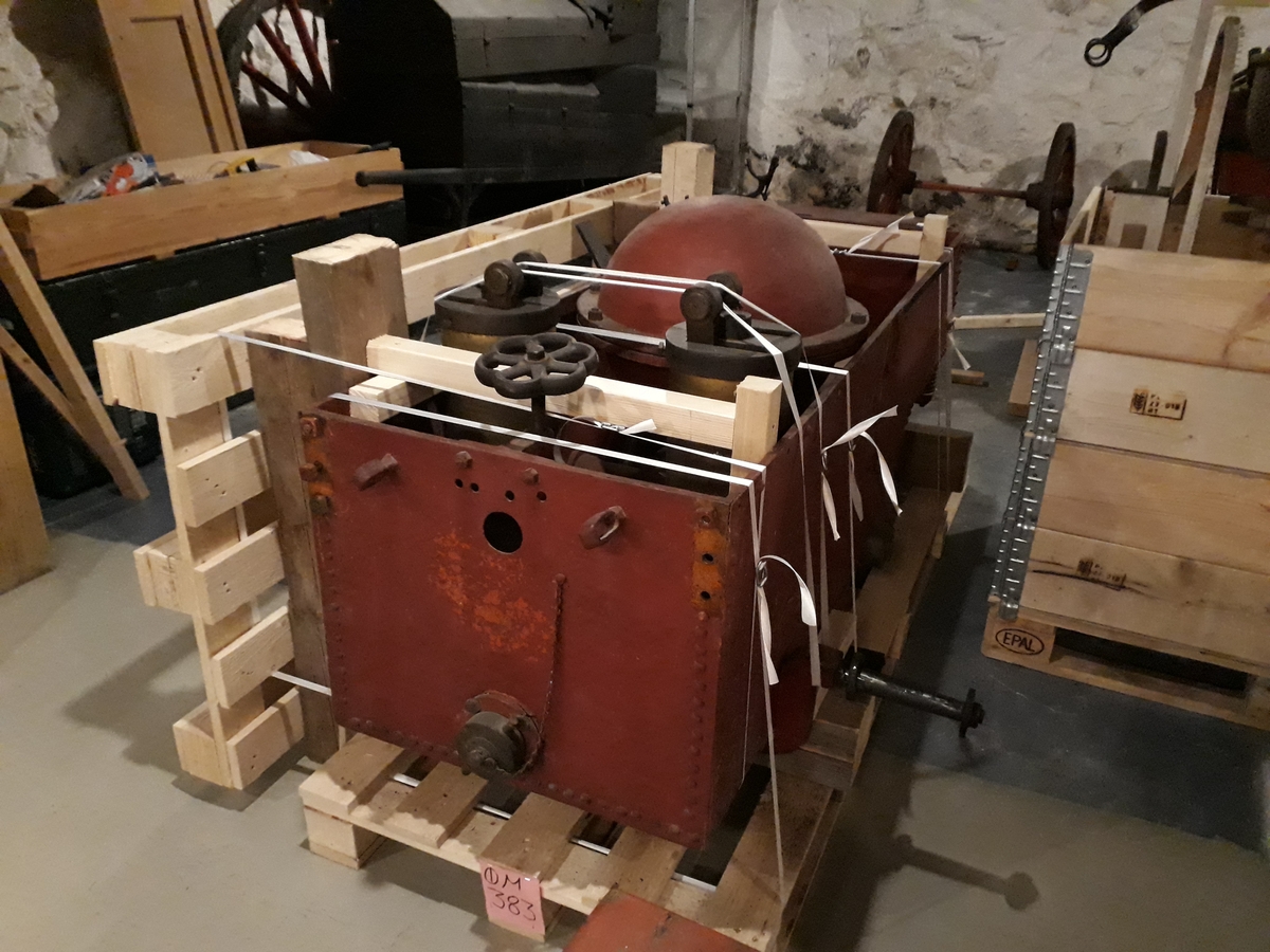 Pumpevogn i rødmalt metall med 4 jernbeslåtte hjul, og drag til hest. Påmontert pumpesystem av jern, med utfellbare håndtak. Verktøykasse i tre foran. Bøyler av jern for brannutstyr.
