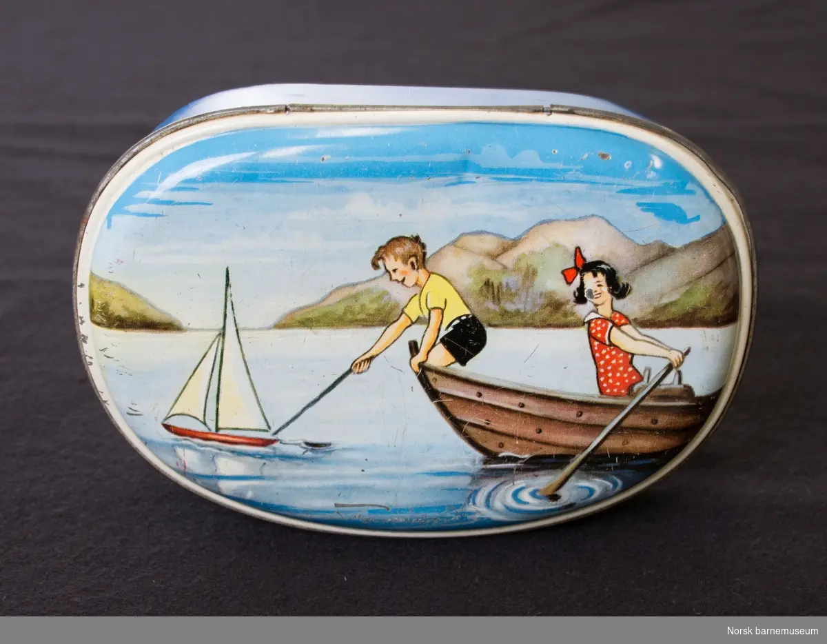Boksen har bilde av jente og gutt som leker i en båt på et vann.