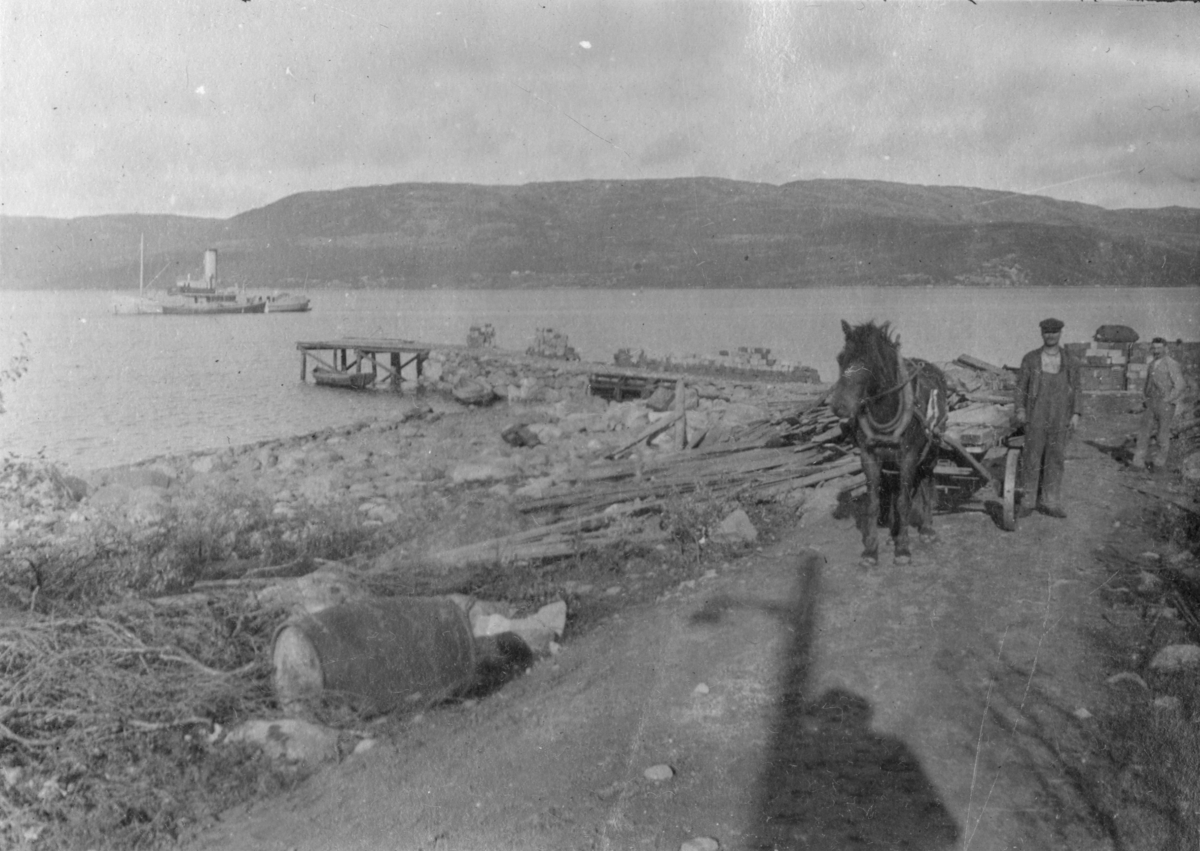 To arbeidere med hest og kjerre på veien, DS "Pasvik" ute på fjorden, åttringen ved kai, lasteprammen og bryggen. Fra byggingen av Tårnet kraftanlegg, Jarfjord, 1919-1920.