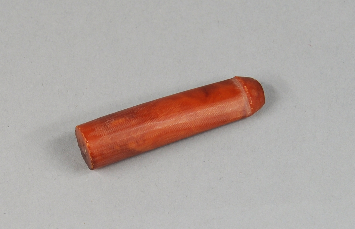 Sylinderformet pipemunnstykke av rav, som er smalere i den ene enden. Den smale enden har en kant ytterst.