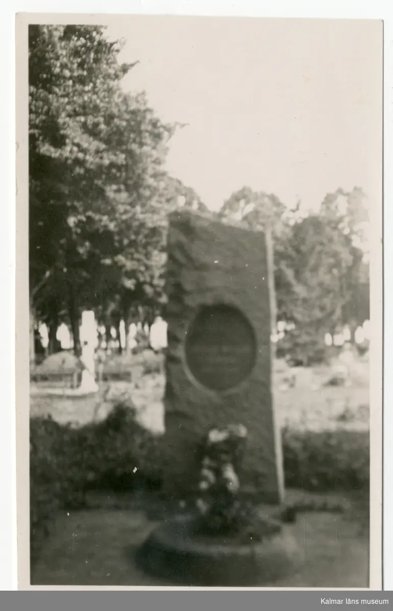 Svart vitt fotografi, föreställande en minnessten/monument, texten på stenen är oläslig p.g.a. att fotografiet är suddigt.