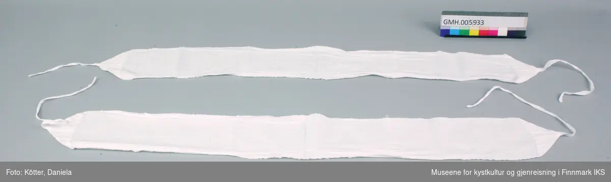 Disse to bind består av lange striper hvit, vevd bomullstøy som er sydd til trekanter i endene. I spissene er det påsydd bomullsbånd. 
I lengda er binden sammensydd av to tøybiter slik at det blir tydelig, at det opprinnelige tøystykket ikke var lengre enn 70 cm. Kantene er sydd med rett tråklesøm. Trekantene er sydd om med geitesøm.