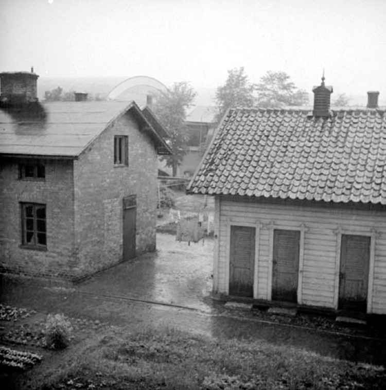 Husen är den sista resten av Tändsticksfabrikens bostäder, de Röda husen i Jönköping, som står inför rivning. Vid ena sidan husen finns en grönsaksodling och på andra sidan hänger tvätt på tork. I bakgrunden skymtar Idrottshuset.