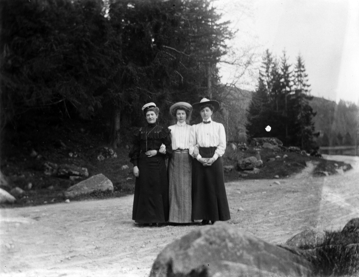 Tre kvinnor på en skogsväg.