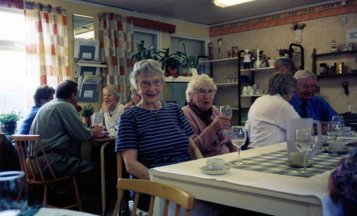PRO Kållered är på utflykt till Önnered i Västra Frölunda år 2004. Från vänster ses Maj-Britt Larsson (i randig tröja) och Inga Andersson sittandes vid ett dukat bord.
(PRO = Pensionärernas riksorganisation)