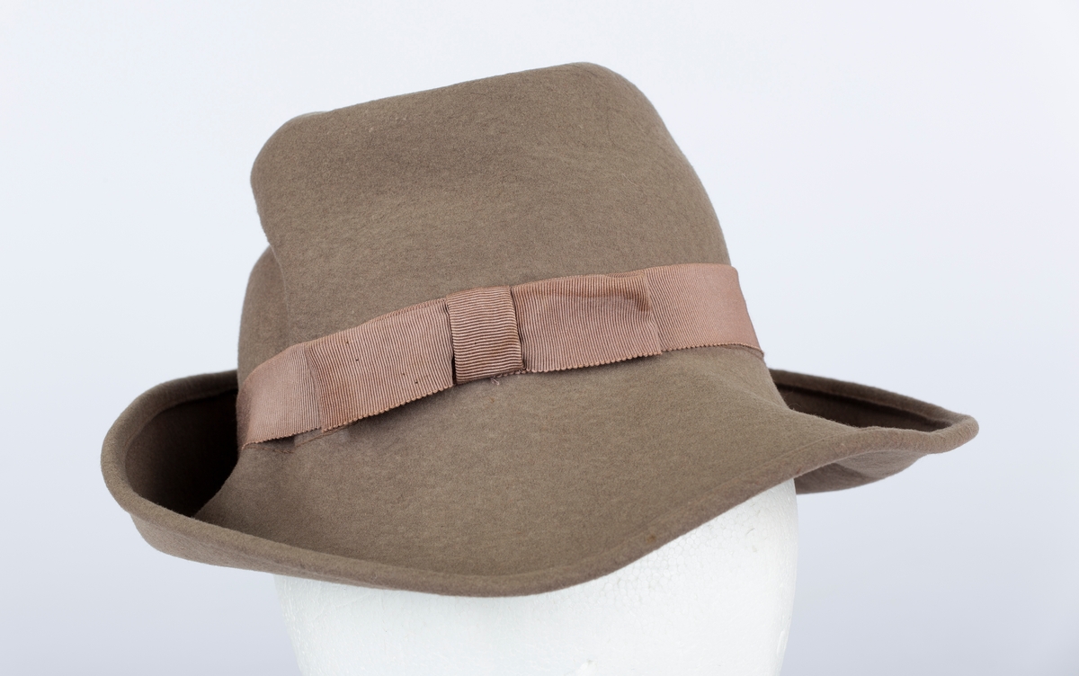 Hatt. Rund hattepull med brem. Bremmen brettet opp. Ripsbånd med sløyfe rundt hattepullen.