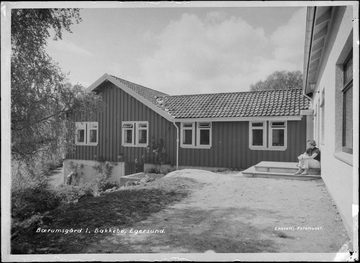 Bærumsgården på Bakkebø hjem og arbeidsskole. En kvinne sitter på trappeoppgangen.