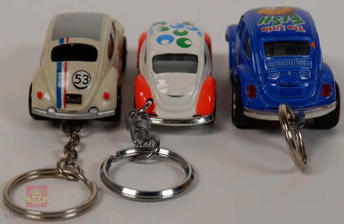 Tre miniatyrbiler av Volkswagen Type 1. Bilene har nøkkelringer for å kunne henges på nøkkelknippe. Alle bilene har forskjellige farger og dekoreringer i hovedfargene blå, hvit og oransje. Miniatyrene er laget av metall og plast.