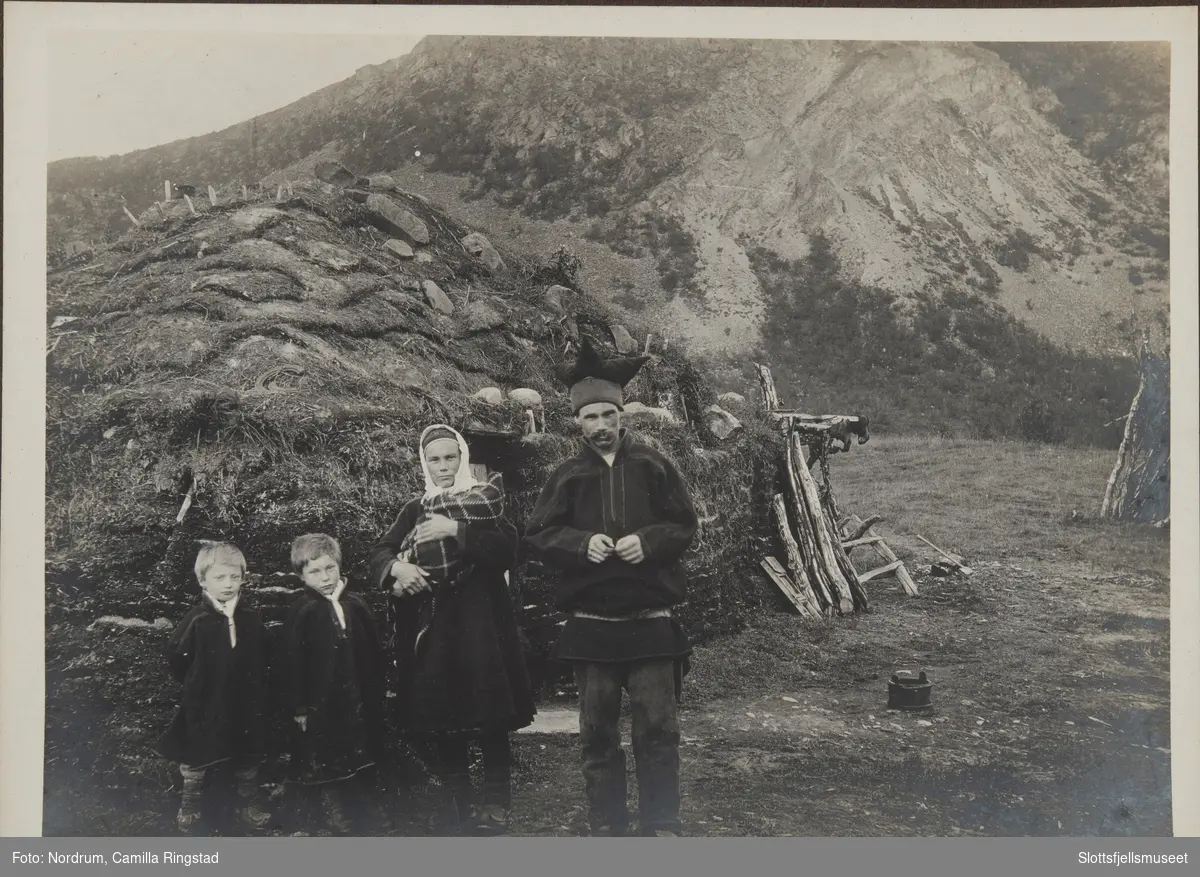 Kvinne og mann, to sønner og en liten baby i Laksefjord utenfor en gamme.