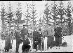 Vintermotiv med personer med ski mot skogsbakgrunn ca. 1895.