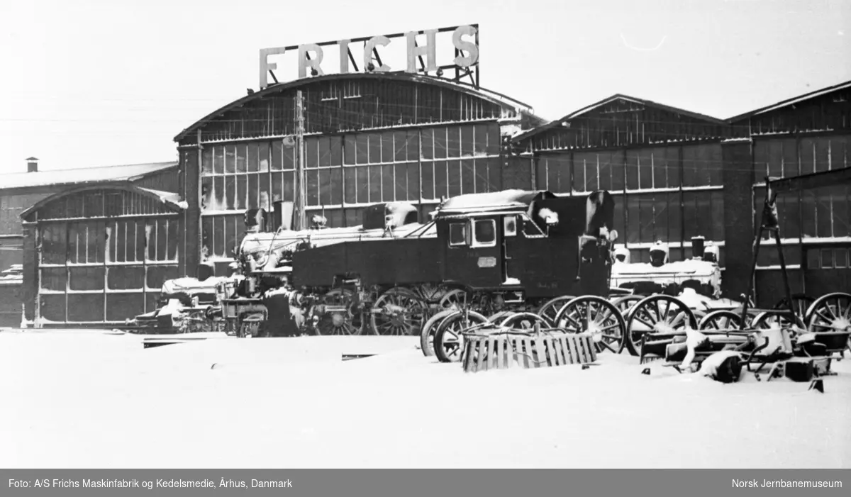 Damplokomotiv type 32b 334 utenfor verkstedhallen  A/S Frichs Maskinfabrik og Kedelsmedie, Århus, Danmark. I bakgrunnen 21e 175 (t.h.) og 21e 176