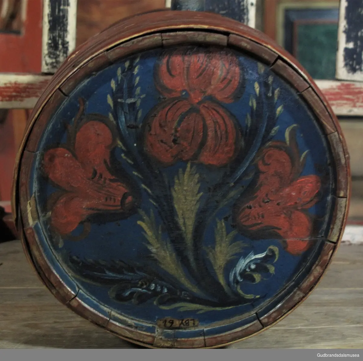 Liten brennevinsdunk i tre med tut av bly; fra Dovre tidlig på 1800-tallet. Rosemalt i rokokkostil dominert av blomstermotiv.