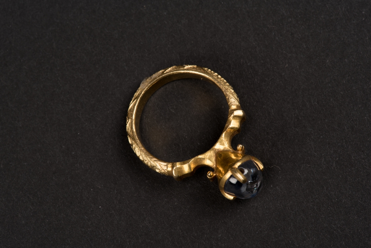 Ring av guld med oval safir.
Safiren vilar i konisk fattning med fyra gripklor. Ursprungligen var troligen ringen belagd med emalj. Ringens utsida har bokstavsfält med betydelsen "safiren vakar över Eder".