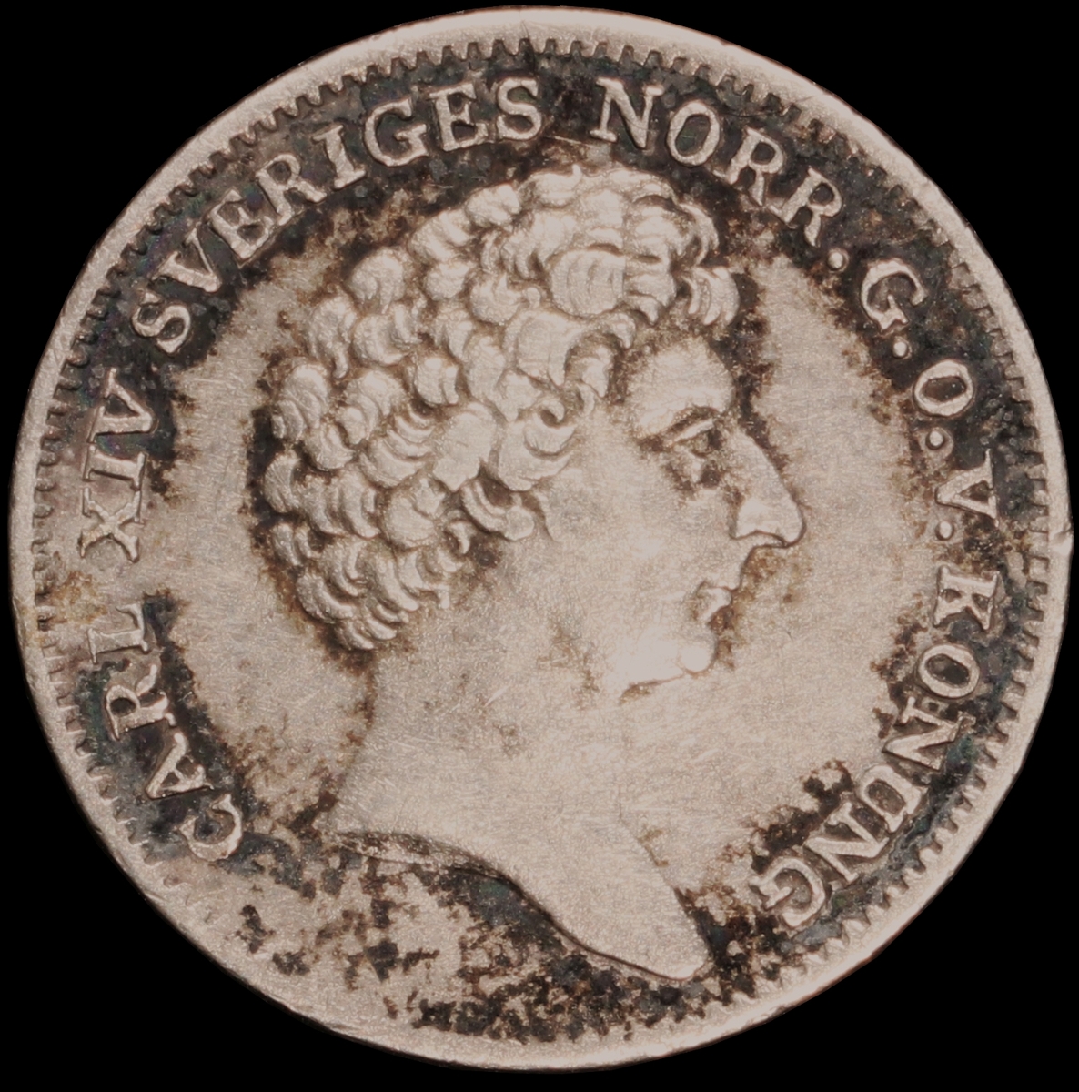 Mynt med valören 1/12 riksdaler specie. Åtsidan har en bild av Kung Karl XIV Johan och frånsidan visar lilla riksvapnet, valör samt kungens valspråk "Folkets kärlek min belöning".