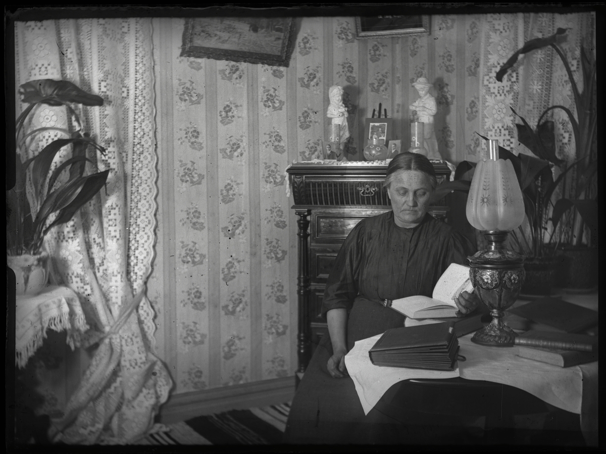 Kvinna läser bok vid fotogenlampa