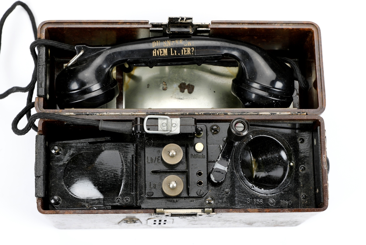 Tyskprodusert felttelefon FF33 (Feldfernsprecher 33). Telefonen er innebygd i en bakelittkasse og mangler bæresele. På lokket er det montert en metallplate med fonetisk alfabet og uttale til ordene og en hvit kodeplate.