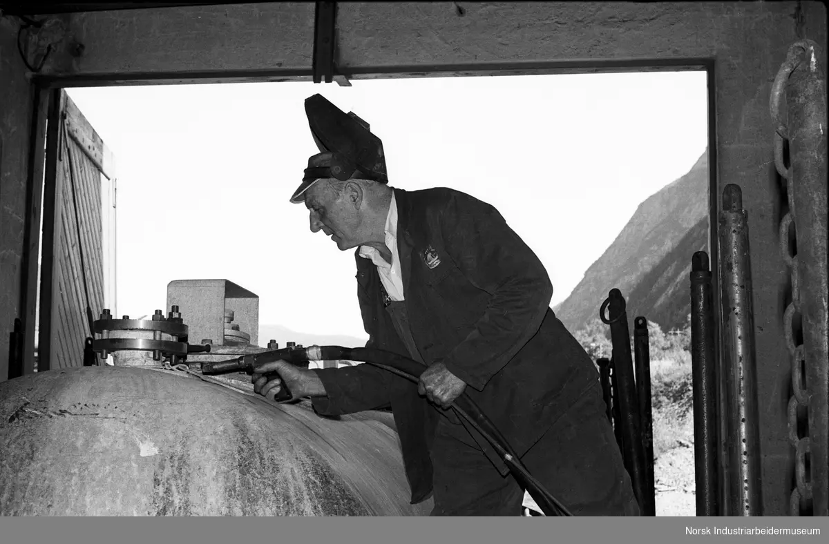 Mann med sveiseutstyr som demonstrerer arbeid på en tank.