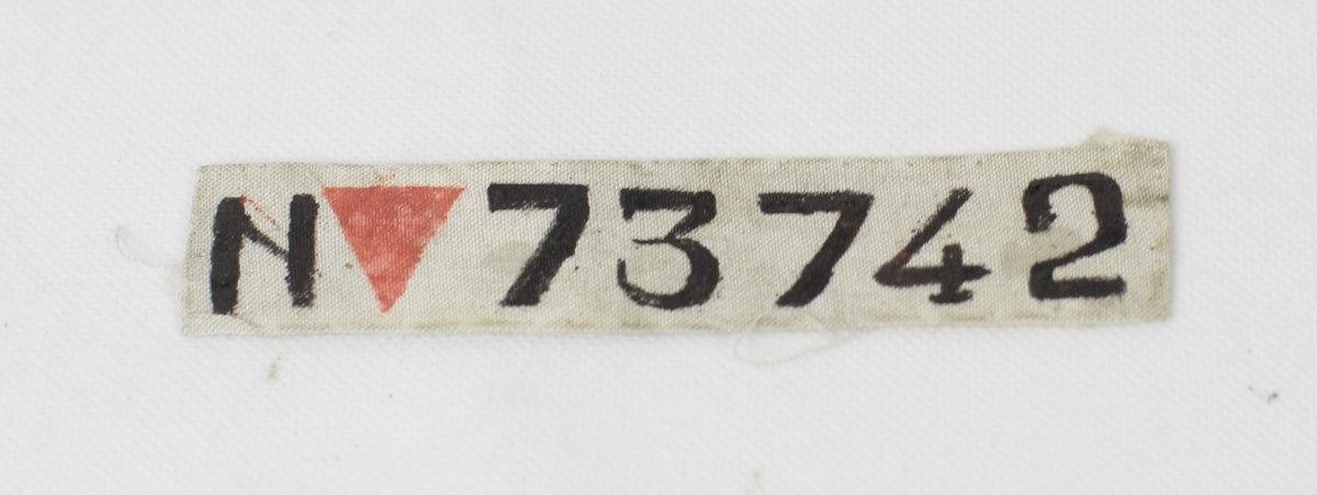 Tøymerke med tekst, "N", rød trekant og "73742". Bokstav og tall i svart. Dette er Frank Storm Johansens fangenummer fra Sachsenhausen (1943-45).