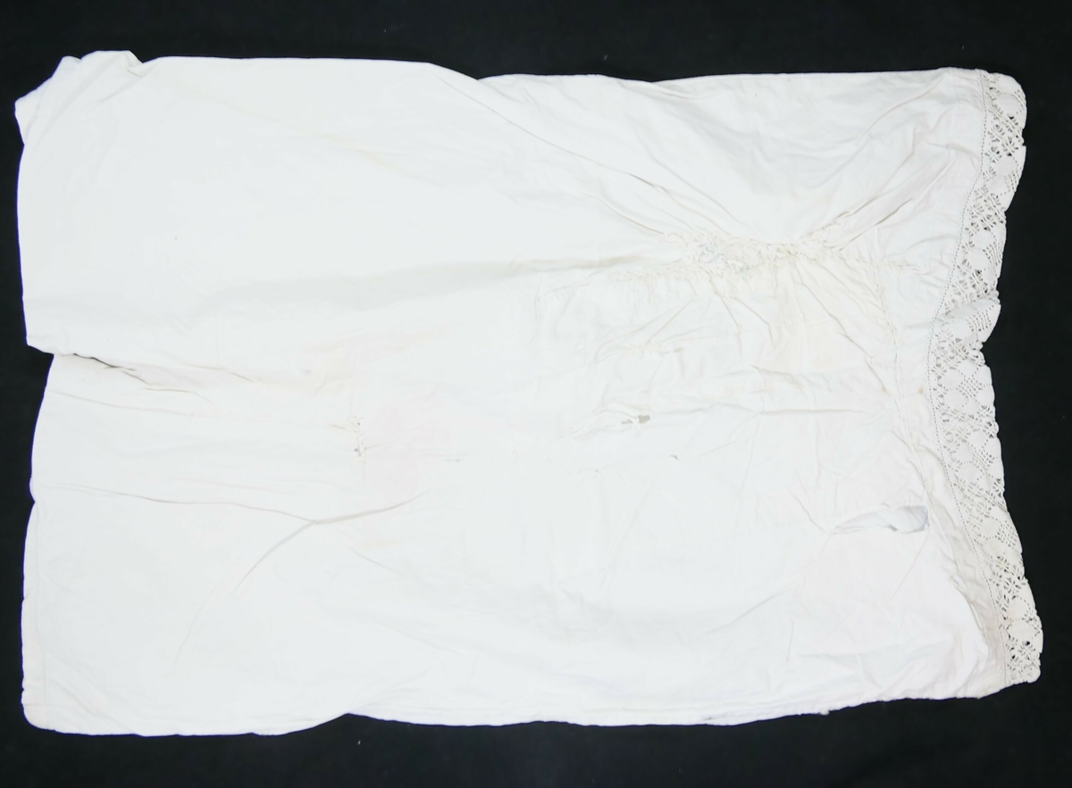 Rektangulært putevar i hvit tekstil med blondekant på den ene kortsiden. 