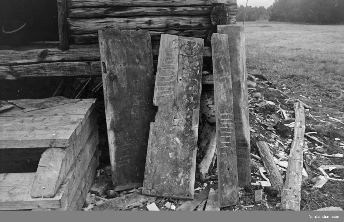 Løse fjøler for Korshuset, Misvær. Fjølene står/ligger utenfor ei tømmerbygning. Litt av ei tretrapp og ei dør ses til venstre. Eng til høyre.