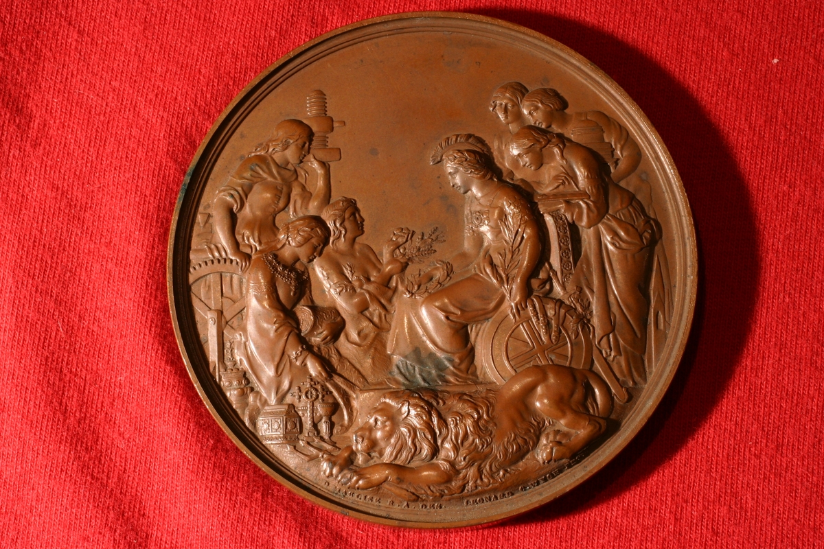 Bronsemedalje fra utstilling i London 1862. På advers Britannia sittende med en løve ved sine ben. Seks kvinner står rundt henne. På revers krans av eikeløv.