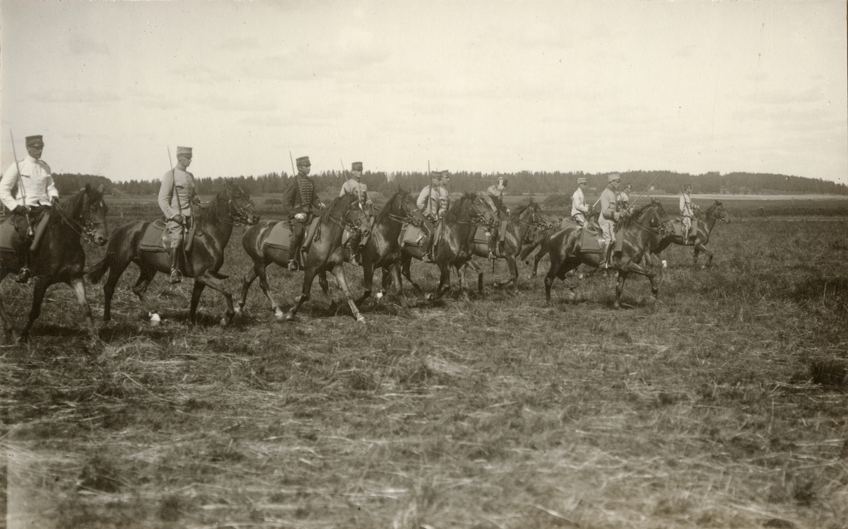 Soldater till häst rider över övningsfält.