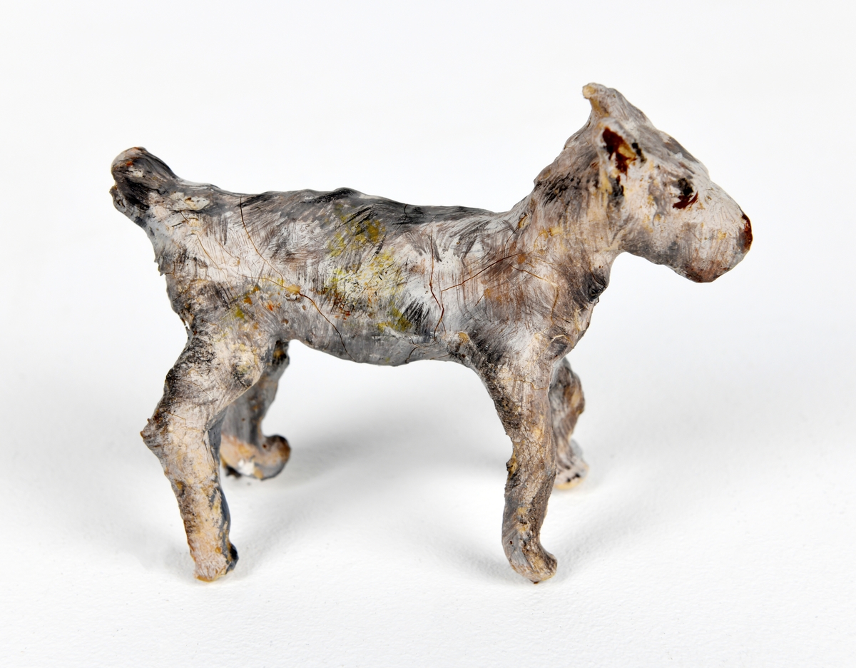 En hund av pappmasje laget av en elev (i formingsfag). Figuren har et skjelett av ståltråd med flere lag papir utenpå. Hunden er malt i ulike nyanser av grått med detaljer i svart.
