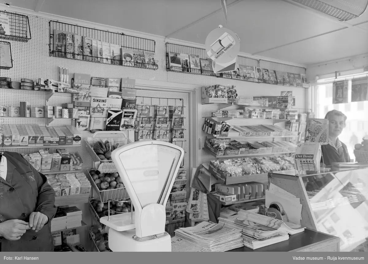 Narvesen kiosk, Vadsø 13.mai 1965. Deler av interiøret og vareutvalget i kiosken. Kioskansatte Anny Iversen og Pauline (Bølla) Stock.