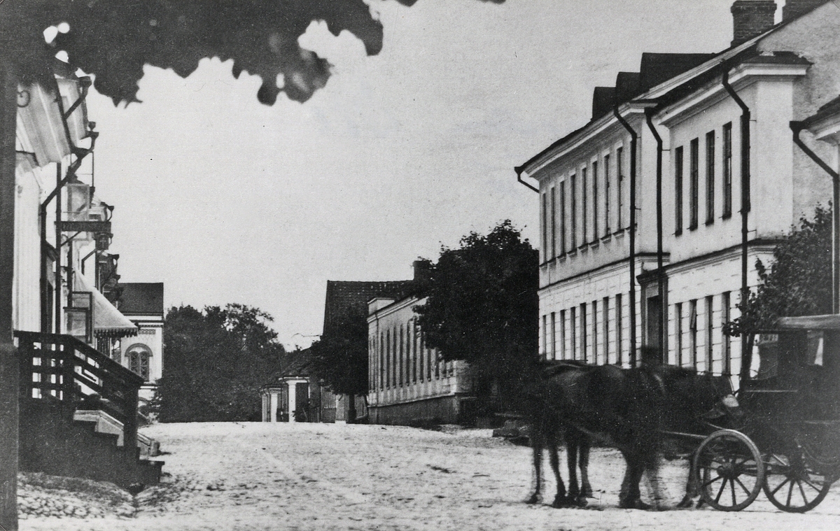 Norrgatan, Växjö, med vy mot öster. I bakgrunden skymtar man nuv. Norrtullskolan. 1870-tal.
Till vänster skymtar några hus i kvarteret Vinaman. Till höger syns husen i kvarteret Sunaman, följt av (trol.) norra 
längan på residenset. En hästskjuts är på väg längs gatan.