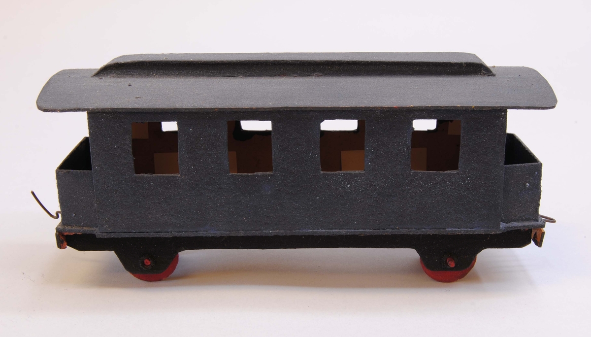 Blå personvagn av papp.
Delarna är limmade eller sammanfogade med rött lack. Hjulen är gjorda av papp och hjulaxlarna av fyrkantiga träpinnar, troligtvis tändstickor. Vagnen är målad blå med mörkgrått tak, svart underrede och röda hjul. Under vagnen är datumet "22/3 1920" handskrivet.
På kortsidorna av vagnen finns böjd ståltråd, en krok och en ögla för att koppla samman vagnen med andra vagnar eller lok. Vagnen har ett förenklat lanternintak, öppna plattformar med fotsteg och fyra fönster på varje sida.