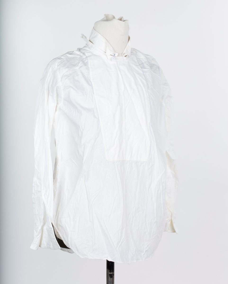 Skjorte. Smoking- eller Gallaskjorte, herre, Hvit bomull, bak-kneppet med stivt skjortebryst, halslinning  og løs snipp. Mrk: Golf de Luxe.