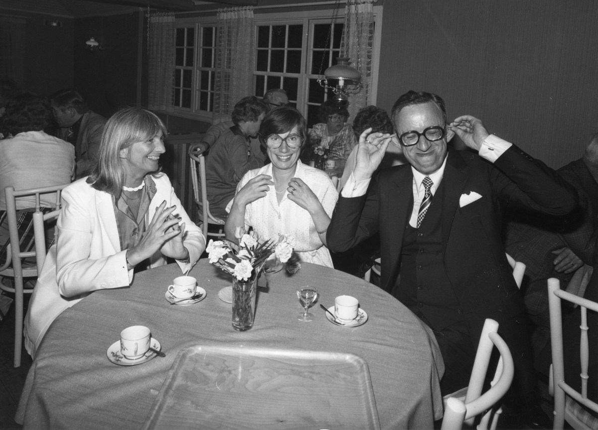 Inomhusbild från Folkets Park i Linköping, 1970-tal. Två kvinnor och en man runt ett runt bord, kaffekoppar och avec på bordet.