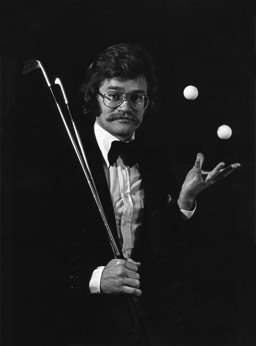 Foto på Johnny Lonn, en magiker. Han håller i två golfklubbor och det är två golfbollar i luften.