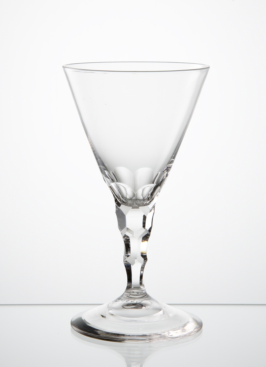 Design: Ingeborg Lundin.
Cocktailglas, konande kupa med fasettslipad nedre del. Fasettslipade fjäll runt benet. Kulslipad botten.