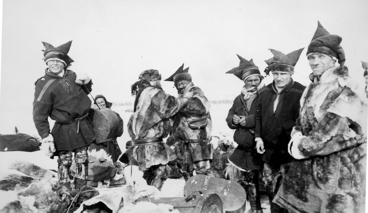 Gruppebilde av samiske gutter og menn, tatt utendørs om vinteren.