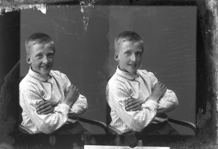 Porträtt av en pojk som sitter i en stol med armarna i kors. Två bilder på samma glasplåt.