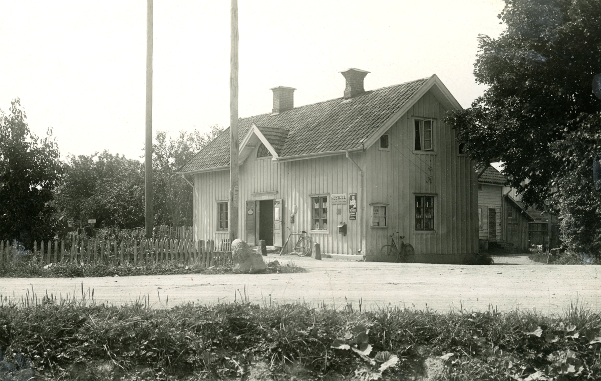 Arvid Andrées handelsbod i Öjebro omkring 1925. Vid husknuten anas annonsering för några av tidens storsäljare, margarin från Mustads fabrik i Mölndal samt tvättmedel och krämer från tekniska fabriken Helios i Sundbyberg.