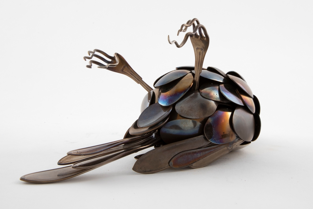 Skulpturen representerer en død fugl som ligger på ryggen med beina opp.