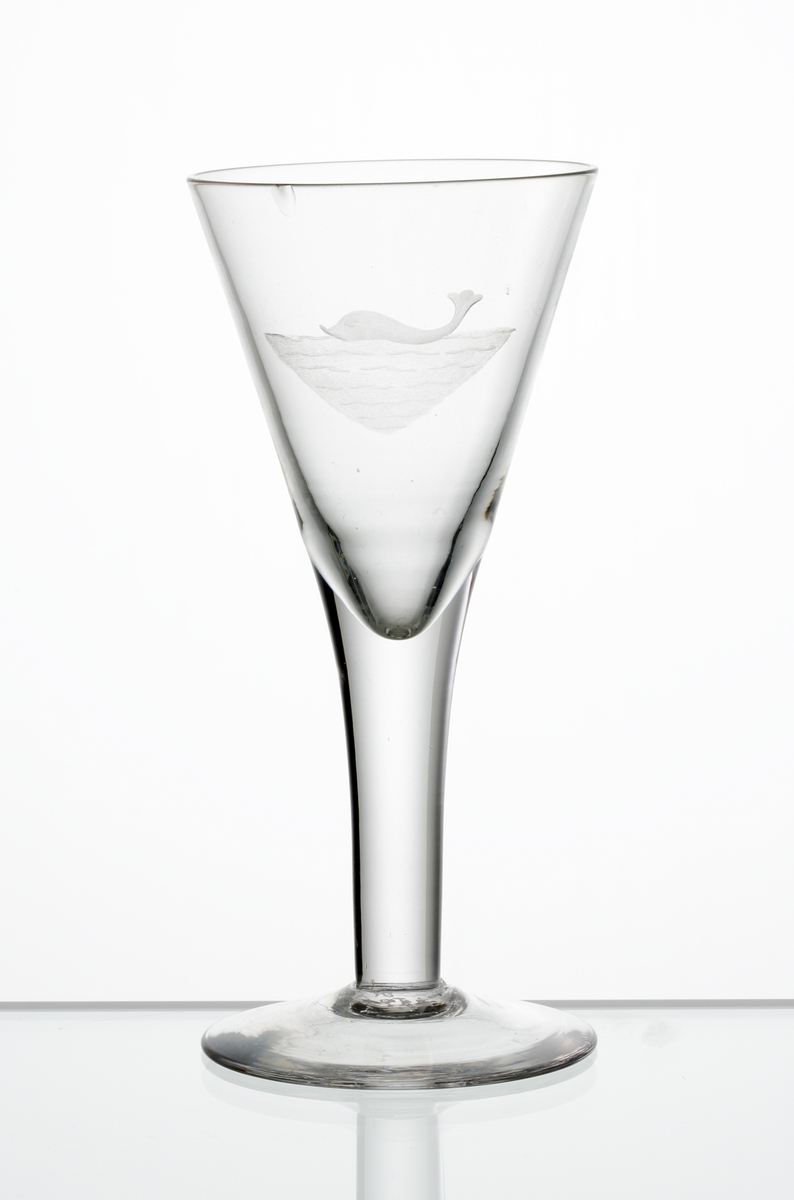 Design: Edward Hald.
Brännvinsglas, konande kupa. Graverad delfin (?) i vatten på kupan.