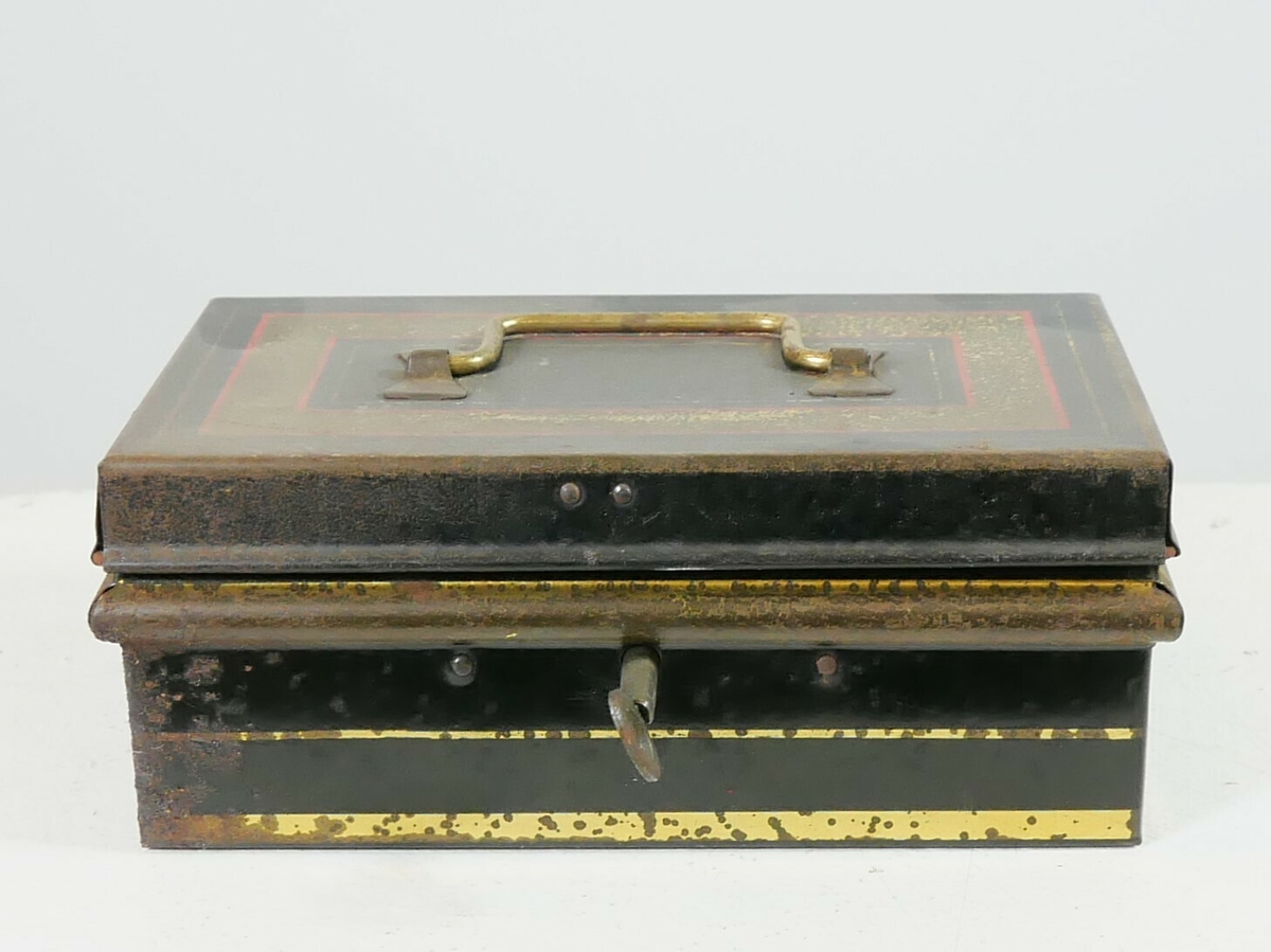 Rektangulært svart skrin med gullfargete kanter og dekor. Skrinet har en lås med nøkkel og et håndtak øverst. Inne i skrinet er det smykker og flere brev. 
