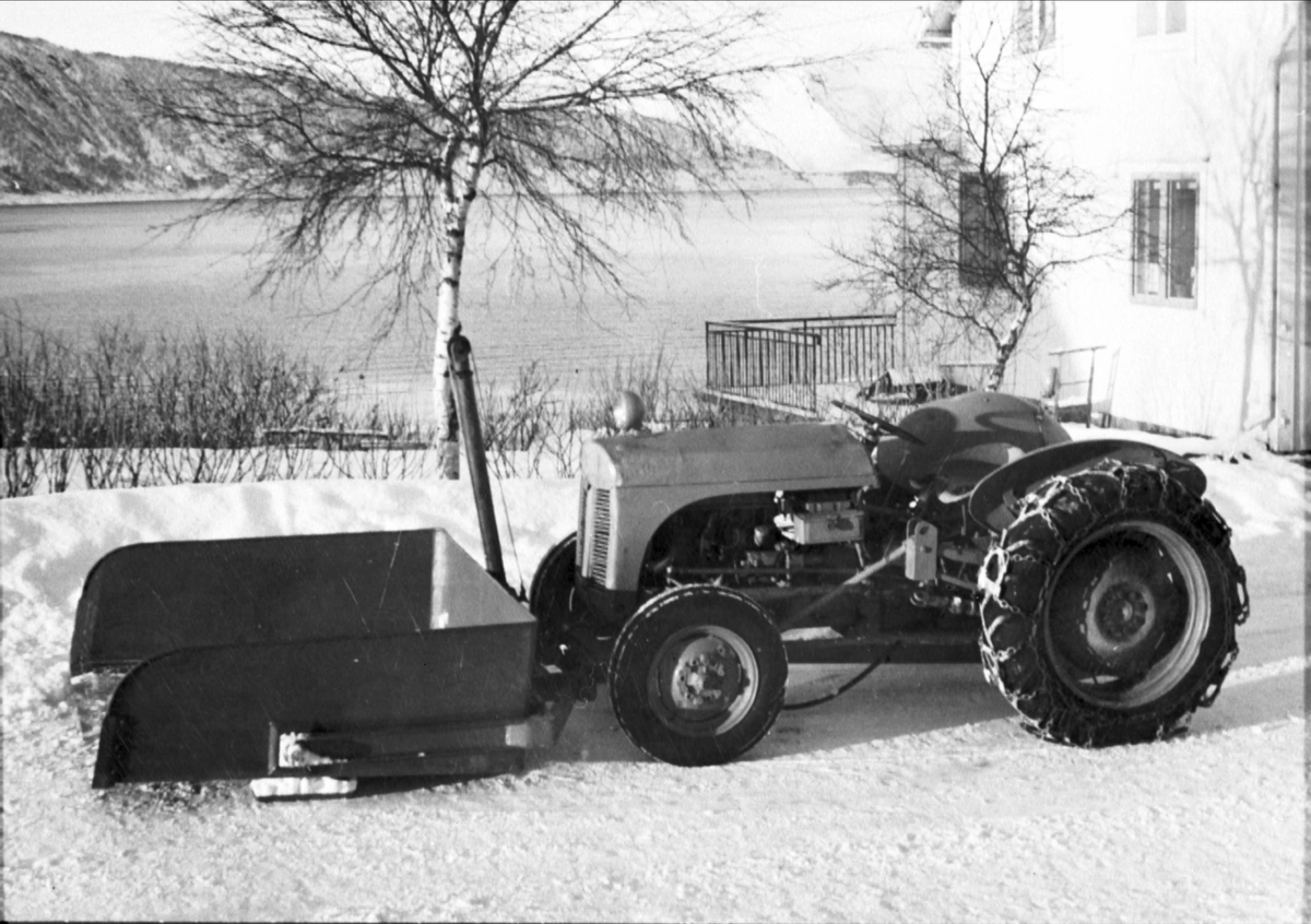 Traktor, med frontmontert snøskuffe og hydraulisk tipp produsert på Borkenes Mekaniske Verksted. Kveøya i bakgrunnen.